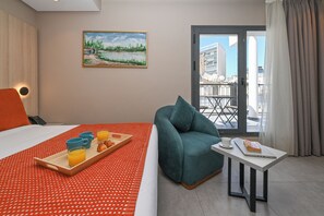A hotel room with a bed, breakfast tray, teal armchair, and a table with a laptop. - Boutique Hotel Aruba Casablanca (Casablanca)