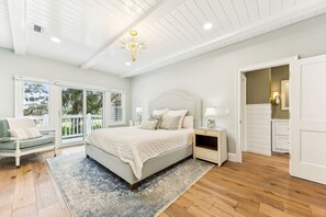 Une chambre spacieuse avec un grand lit, une table de chevet, une chaise et une vue sur l’extérieur grâce à une porte-fenêtre coulissante.