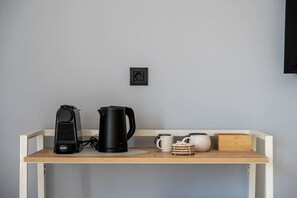 A kitchenette with a coffee maker, a kettle, and a small cabinet with mugs and a tea pot. - The Stone Suite | Avra Suites (Kos)