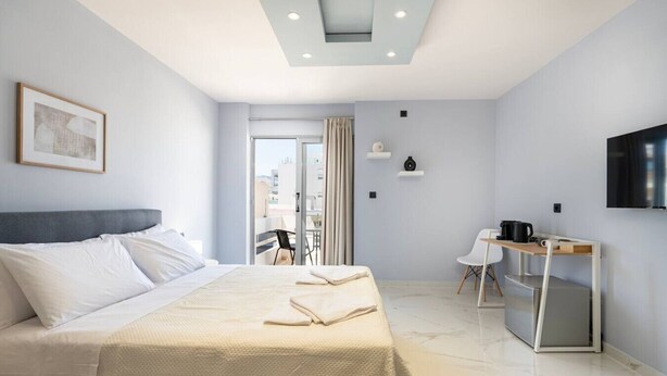 Ein modernes Hotelzimmer mit einem großen Bett, einem Schreibtisch mit Stuhl, einem Fernseher und einem Balkon mit Aussicht.