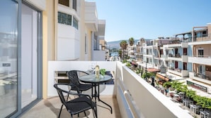 Ein Balkon mit Tisch und Stühlen, der auf ein Wohngebiet mit mehreren Gebäuden und einem klaren Himmel blickt.