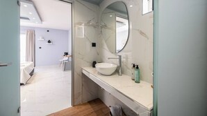 Ein modernes Badezimmer mit Waschtisch aus Marmor, einem großen Spiegel und einem weißen Waschbecken.