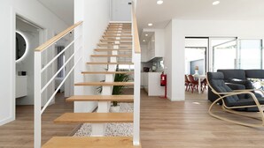 A modern interior with a wooden staircase, a dining area, and a living space with a rocking chair. - Dino Beach House - Three Bedroom House, Sleeps 6 (Aroeira)