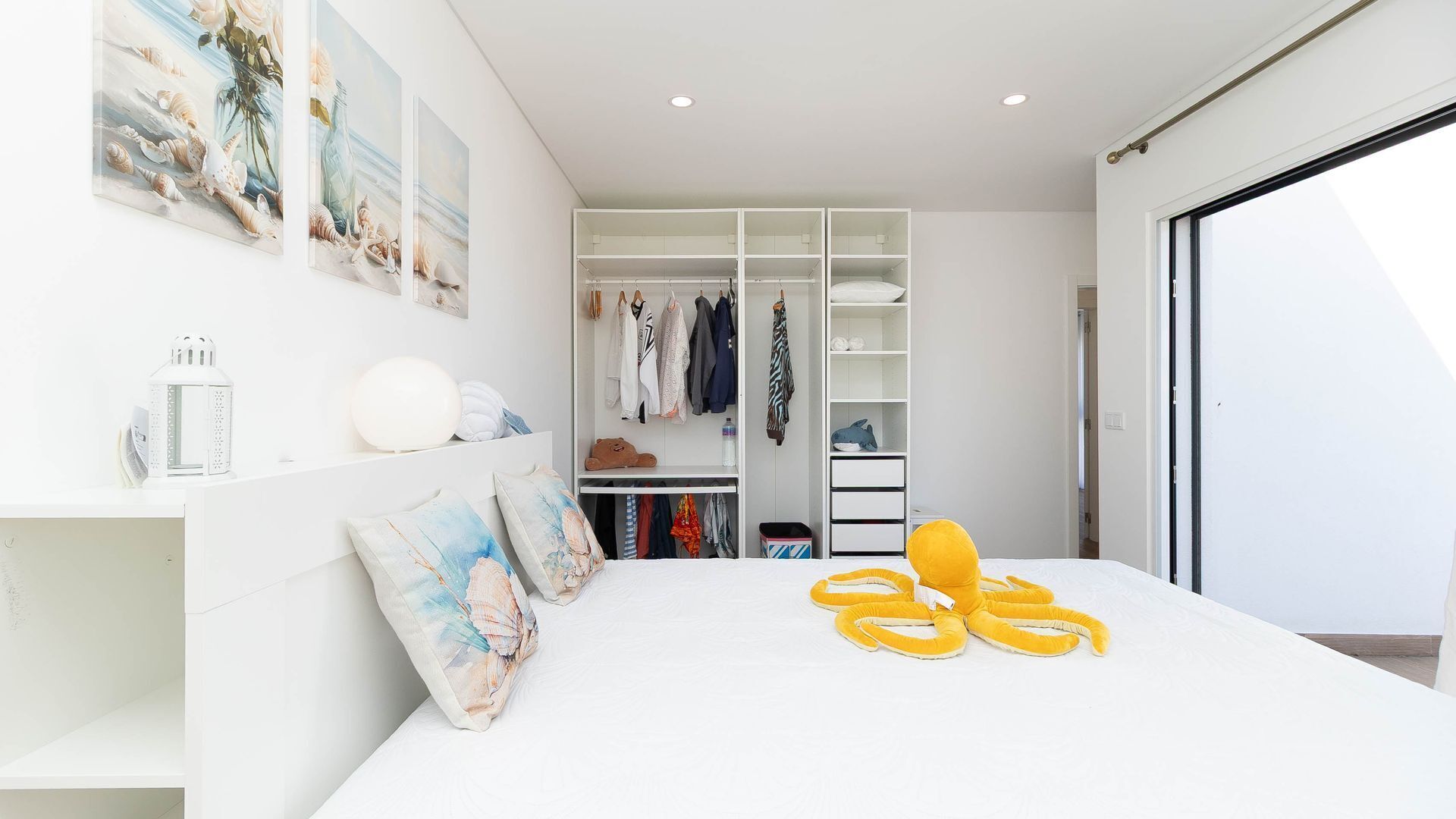 Een moderne slaapkamer met een groot bed, een inloopkast en uitzicht door een schuifdeur.
