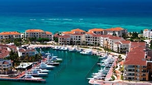 A marina with multiple boats docked, surrounded by buildings with red roofs. - Cap Cana | King Bed | Pool & Jacuzzi (Punta Cana)