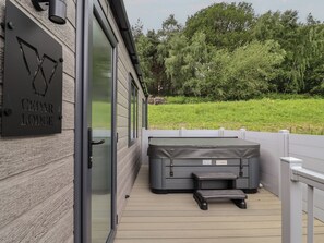 Una terraza de madera con un jacuzzi y una puerta de cristal con un letrero que dice 'Cedar Lodge'.