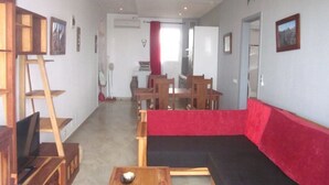 A room with a red sofa, wooden tables, a TV, and a staircase. - Superb apartment with sea view, right in the center of town (Antsiranana)