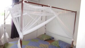 A single bed with a canopy and a checkered bedspread. - Superb apartment with sea view, right in the center of town (Antsiranana)