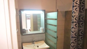 A bathroom with a white sink, a mirror, and a patterned shower curtain. - Superb apartment with sea view, right in the center of town (Antsiranana)