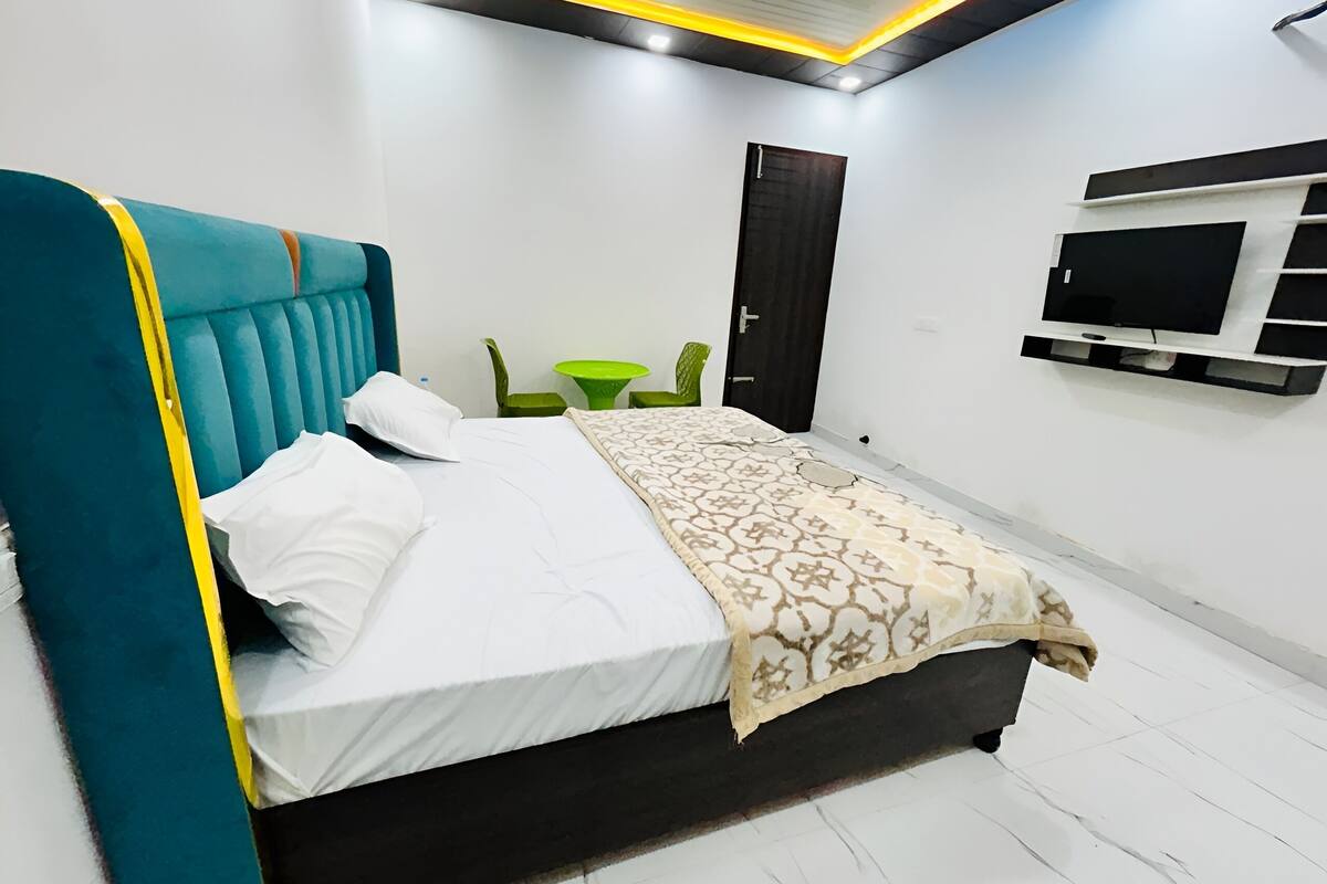 A neatly arranged bedroom with a bed, a TV mounted on the wall, and a door.
