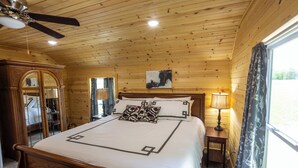 Un dormitorio con paneles de madera, una cama, una mesita de noche, una lámpara, un espejo y un ventilador de techo.