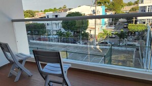 A balcony with two chairs, a view of a street with cars and buildings, and a metal railing. - Mirador Baluarte Pool& Parking (Cartagena de Indias)