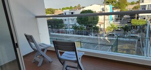 A balcony with two chairs, a view of a street with cars and buildings, and a metal railing. - Mirador Baluarte Pool& Parking (Cartagena de Indias)
