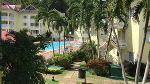 A resort with a swimming pool, palm trees, and a pathway leading to the pool. - Live Easy at the mystic (Ocho Rios)