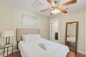 A hotel room with a bed, a ceiling fan, a painting, a mirror, and a bedside table. - Quiet Retreat Near Downtown Charleston (North Charleston)