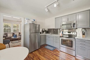 A modern kitchen with stainless steel appliances, grey cabinetry, and a wooden floor. - Quiet Retreat Near Downtown Charleston (North Charleston)