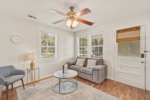 A room with a ceiling fan, a sofa, a coffee table, and a door with blinds. - Quiet Retreat Near Downtown Charleston (North Charleston)