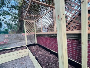 Una estructura de madera con techo de celosía, pared de ladrillo y piso de madera.