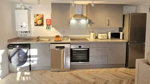 A modern kitchen with stainless steel appliances, a dishwasher, an oven, and a microwave. - Stylish and spacious, lower ground floor apartment -Pass the Keys (Shrewsbury)