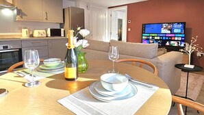 A modern living room with a dining area, a television, and a kitchen in the background. - Stylish and spacious, lower ground floor apartment -Pass the Keys (Shrewsbury)
