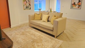 A living room with a beige sofa, patterned rug, and artwork on the walls. - Stylish and spacious, lower ground floor apartment -Pass the Keys (Shrewsbury)