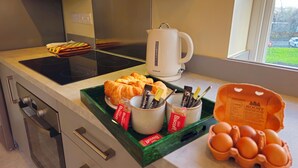 Una encimera de cocina con una bandeja de croissants, una cafetera y un cartón de huevos.