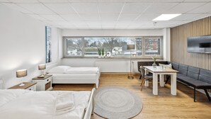 A modern hotel room with two beds, a dining table, a sofa, and a TV. - HanseStay Wandsbek (Hamburg)