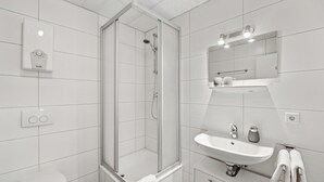 A modern bathroom with a glass-enclosed shower, a white sink, and a toilet. - HanseStay Wandsbek (Hamburg)