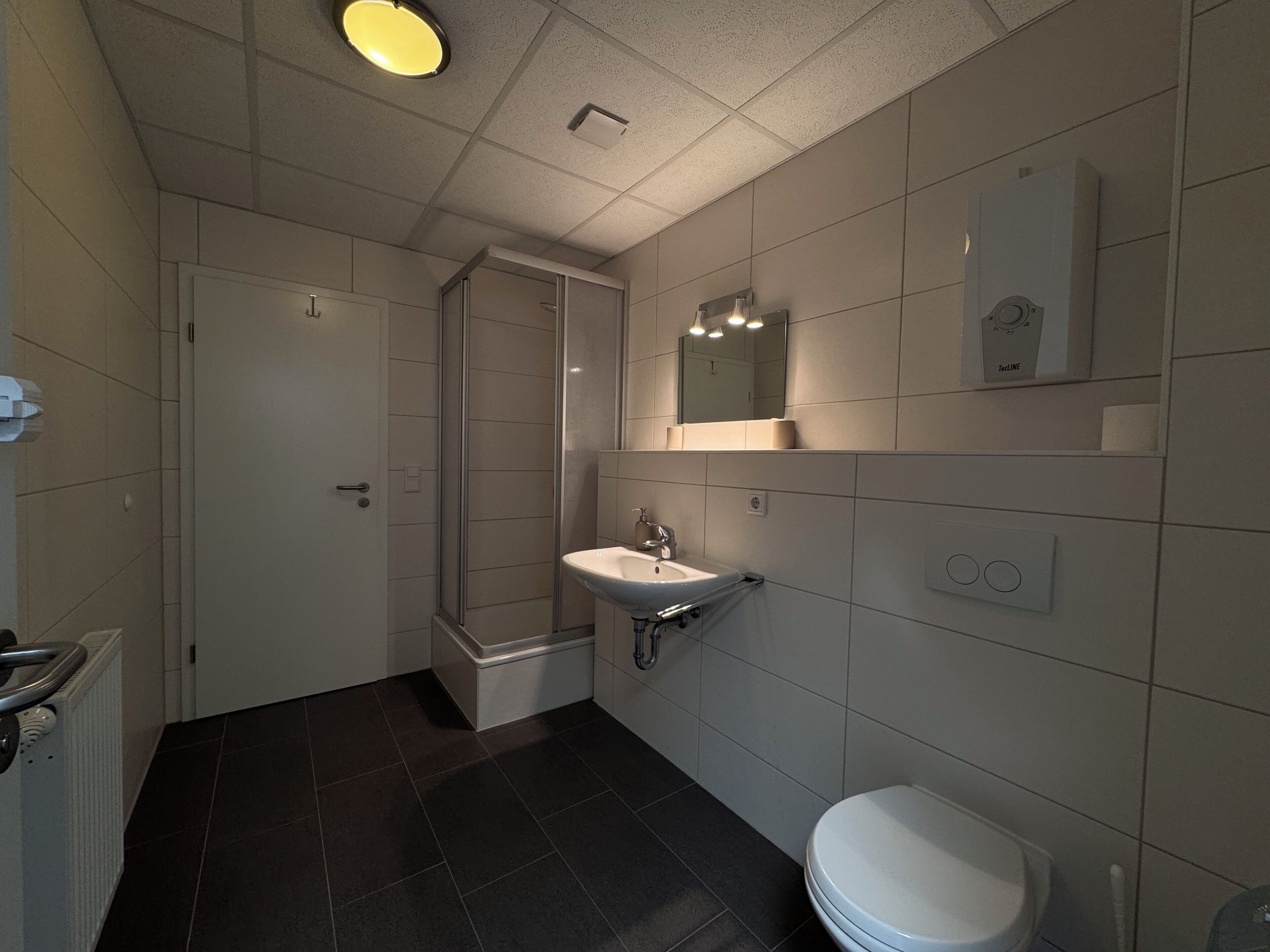 Ein Badezimmer mit Dusche, Waschbecken und Toilette.