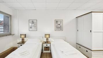 Ein Doppelzimmer mit zwei Betten, Nachttischen, Lampen, gerahmten Bildern und einem Kleiderschrank.