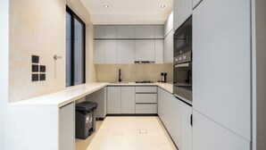 A modern kitchen with grey cabinets, a black stove, and a microwave. - Luxury two bedroom Apartment Al Rawdha (Riyadh)