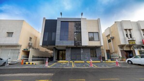 A modern building with a flat roof, large windows, and a parking area with cones. - Luxury two bedroom Apartment Al Rawdha (Riyadh)
