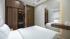 A modern hotel room with a large bed, a wardrobe, a mirror, and a bedside table. - Luxury two bedroom Apartment Al Rawdha (Riyadh)
