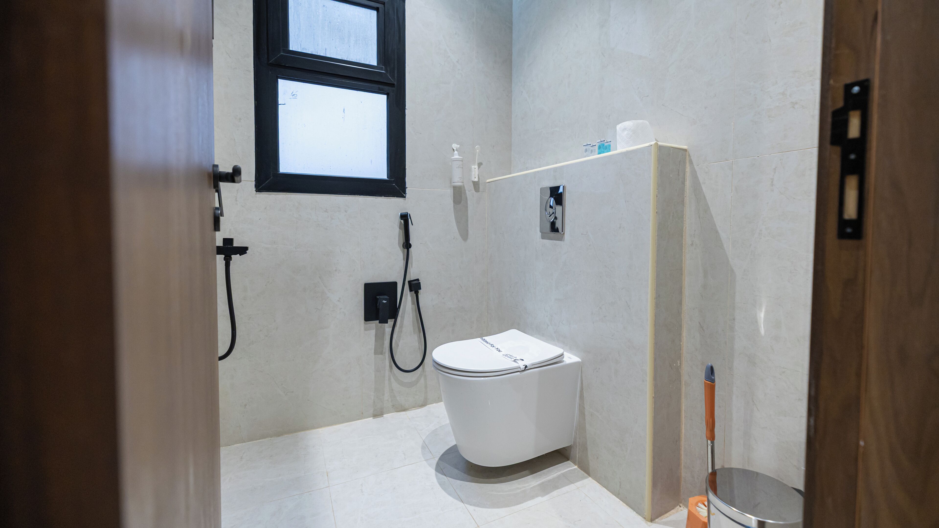 Une petite salle de bain moderne, équipée de toilettes, d’une douche et d’une fenêtre.