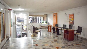 A lobby with a terrazzo floor, seating areas, a reception desk, and a window with a view of the street. - Hotel Dinastia Real (Neiva)