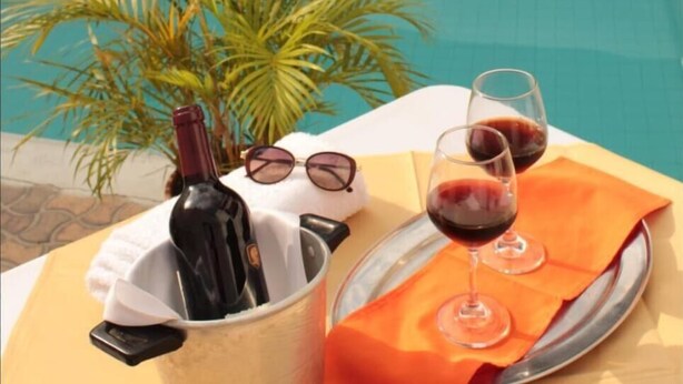 A poolside setting with a bottle of wine, two wine glasses, and a pair of sunglasses on a table. - Hotel Dinastia Real (Neiva)