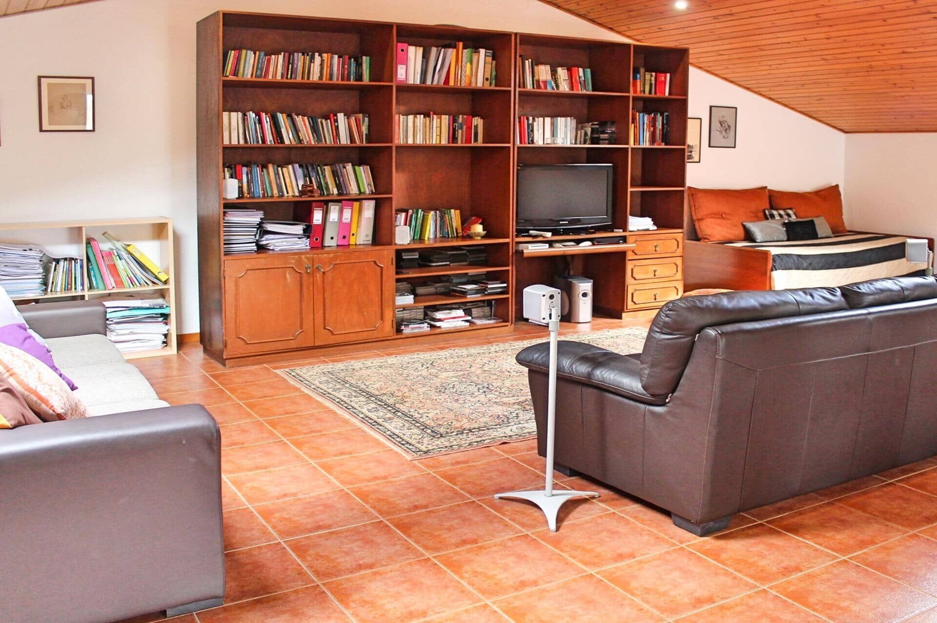A living room with a large wooden bookshelf, a television, a sofa, and a coffee table.