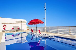 A pool area with lounge chairs and umbrellas, a lifebuoy, and a clear view of the sea. - Villa Sea Shore Dio by Villa Plus (Gaula)