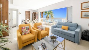Ein geräumiges Wohnzimmer mit Balkon und Meerblick, ausgestattet mit zwei Sofas und einem Couchtisch.