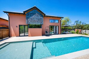 A modern house with a swimming pool, a covered patio, and a decorative facade. - Villa Fire by Villa Plus (Kariotes)