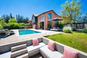 A modern house with a swimming pool, outdoor seating, and a well-maintained garden. - Villa Fire by Villa Plus (Kariotes)
