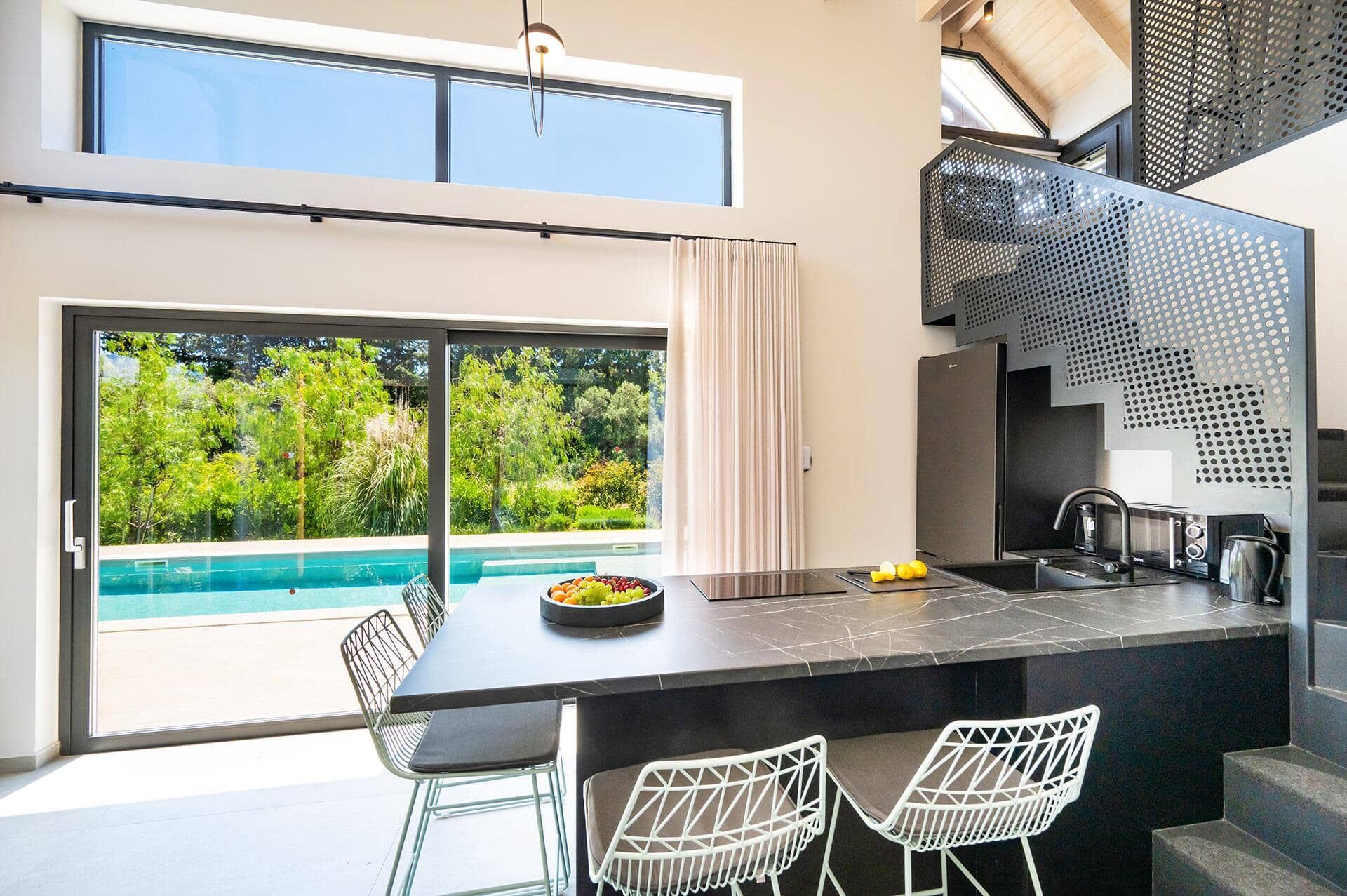 A modern kitchen with a large island, a built-in oven, and a view of a swimming pool.