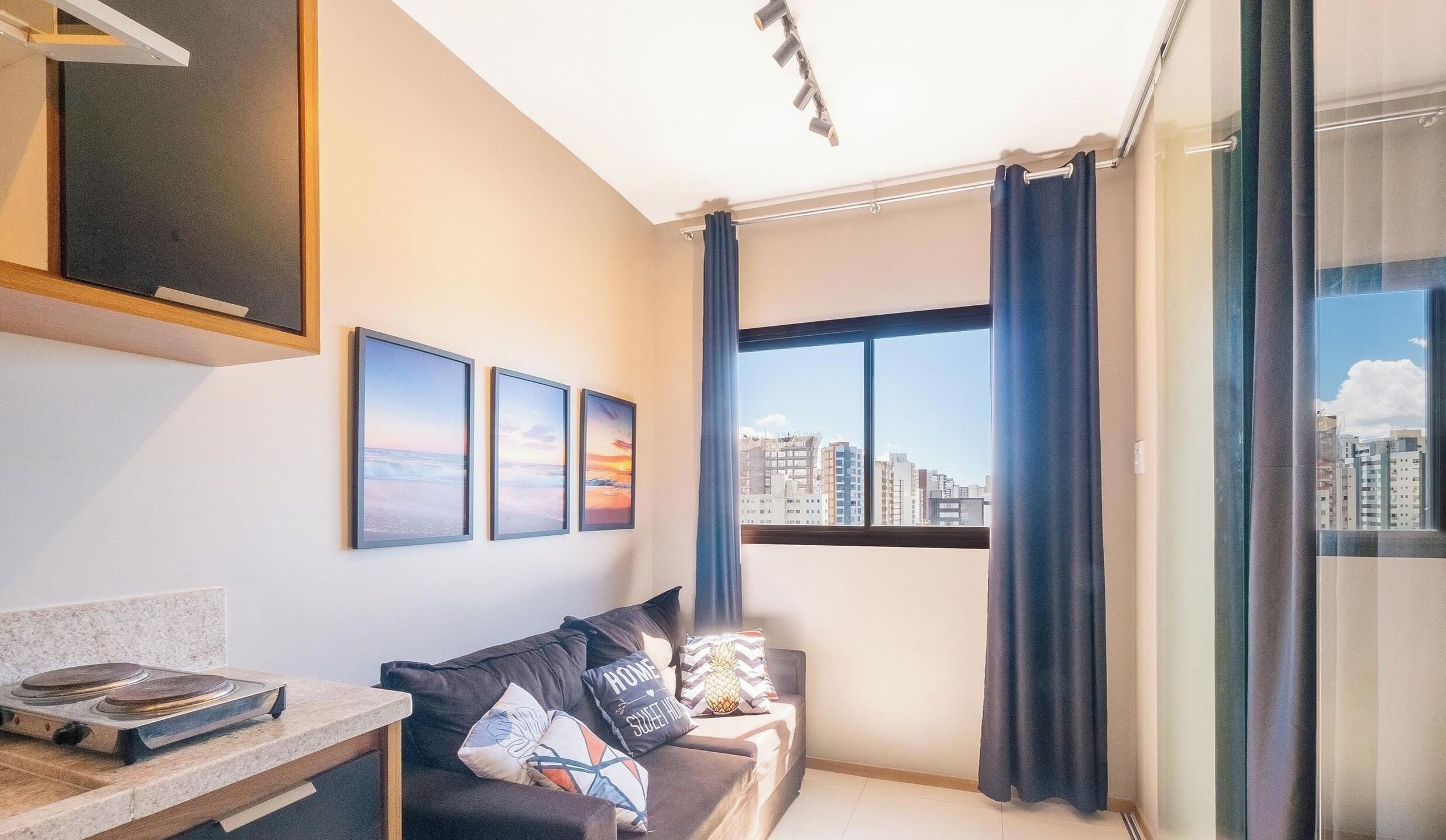 Uma sala de estar moderna com um sofá, uma TV de tela plana e quadros na parede.