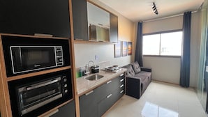A modern kitchen with a built-in oven, microwave, and sink. There is a sofa and a window with curtains. - Apt w/ Partial Sea View 350m From the Beach Hpa904 (Salvador)