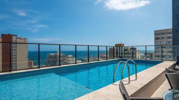 A rooftop pool with a clear view of the ocean and surrounding buildings.