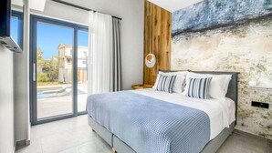 A bedroom with a bed, a large window, a wall with a textured mural, and a ceiling fan. - Villa Water by Villa Plus (Kariotes)