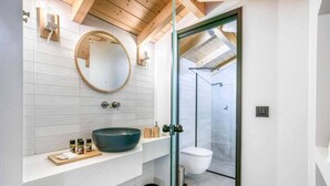 A modern bathroom with a large round mirror, a vessel sink, and a glass-enclosed shower. - Villa Water by Villa Plus (Kariotes)