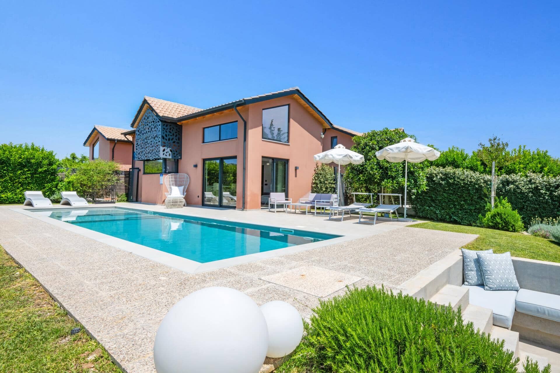 A modern house with a swimming pool, outdoor seating, and a well-maintained garden.
