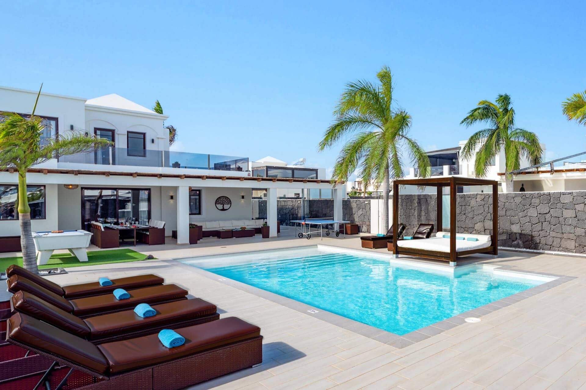 A pool area with lounge chairs, a table, and a canopy structure.