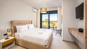 Ein modernes Hotelzimmer mit einem großen Bett, einem Nachttisch, einem kleinen Tisch mit Stühlen, einem an der Wand montierten Fernseher und einem Balkon mit Blick.